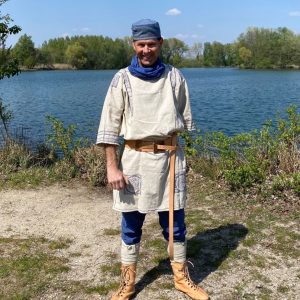 Auf dem Bild ist Ralph Lehr in der Kleidung eines Spätantiken Soldaten zu sehen. Er steht vor einem sommerlichen See.