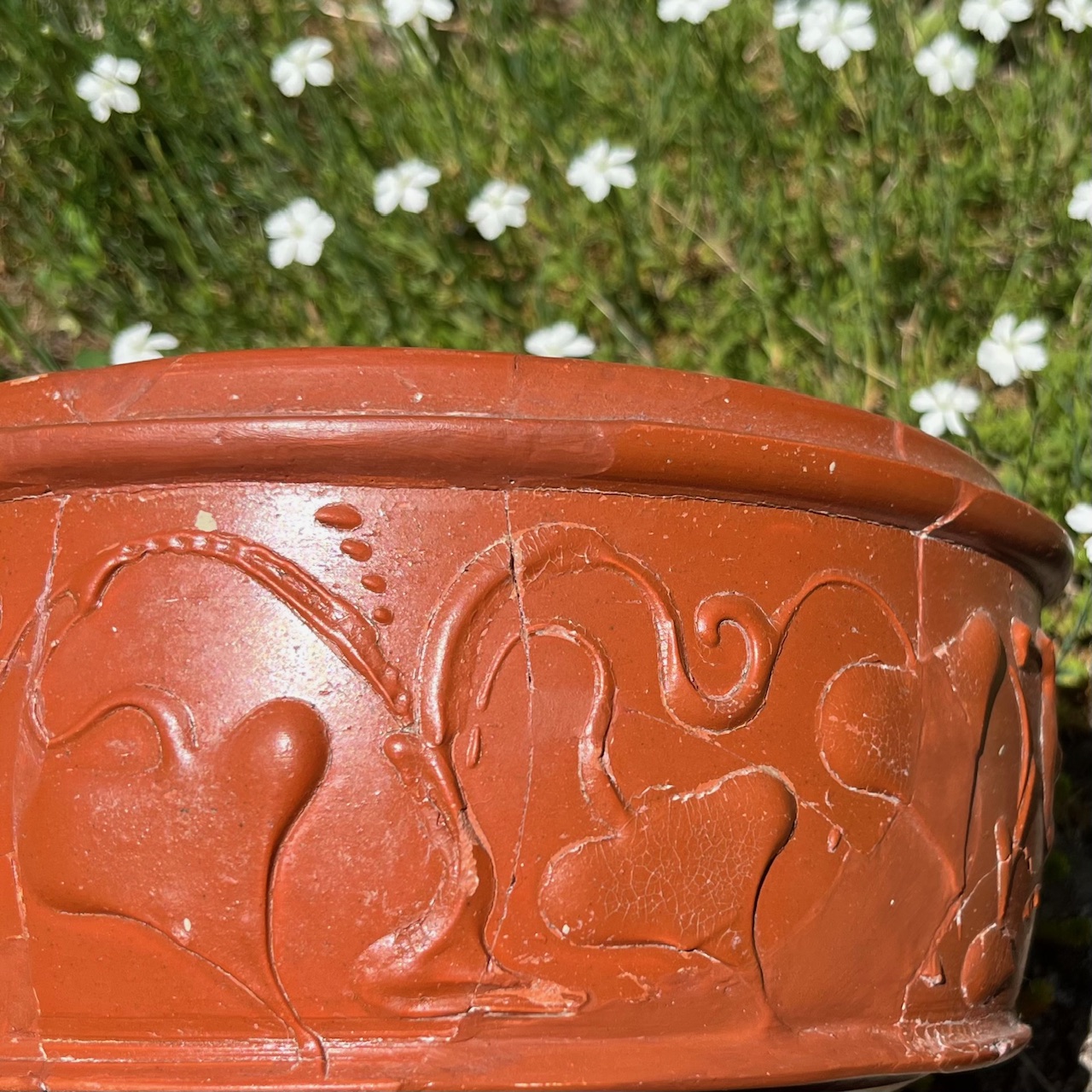 Das Bild zeigt eine Terra-Sigillata-Schüssel, auf der in Barbotine-Technik Efeuranken aufgemalt sind.