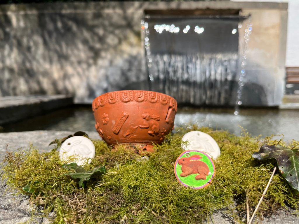 Das Bild zeigt Ton-Medaillons mit Häschen, die bunt bemalt wurden